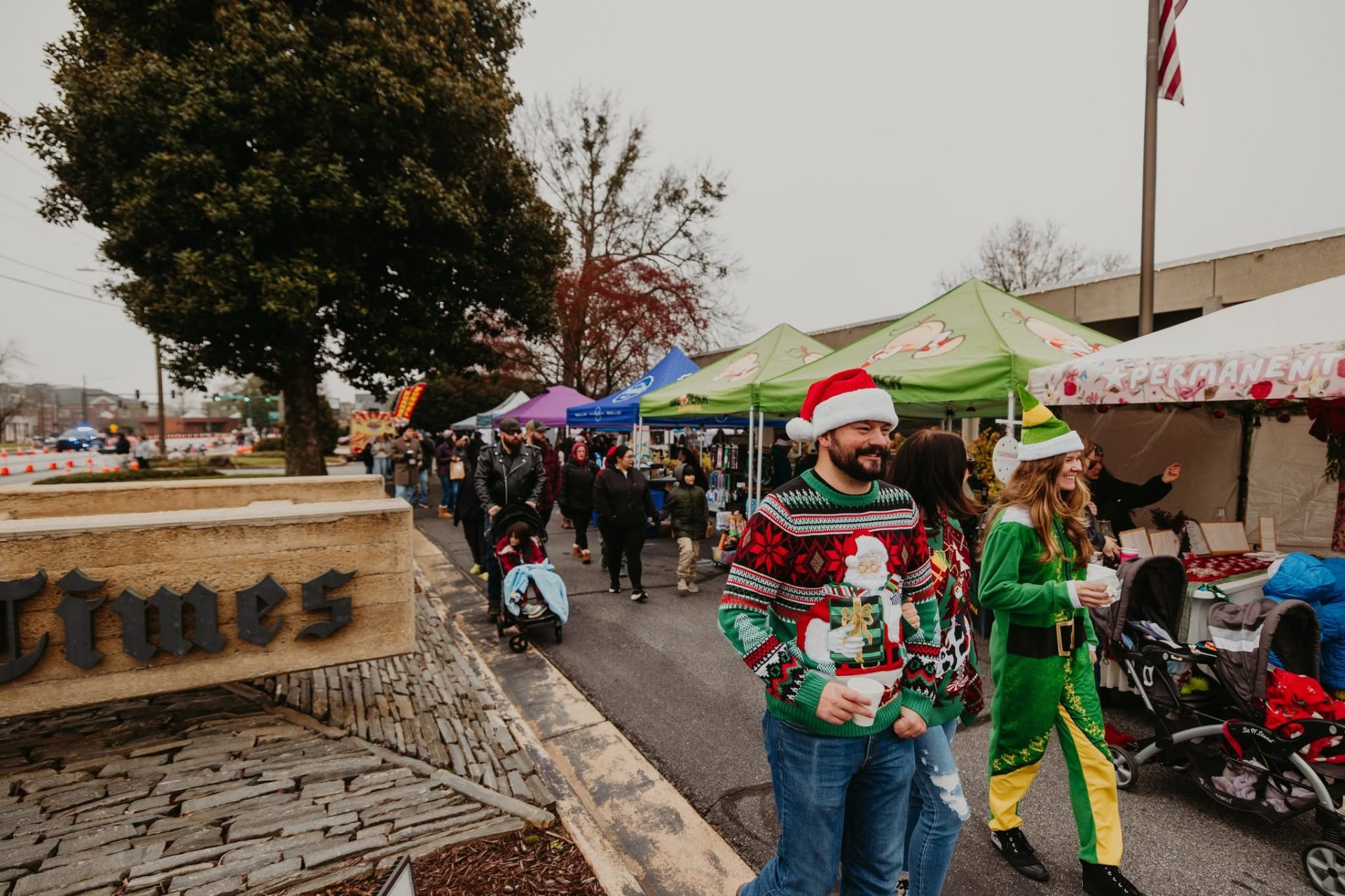 Visitors in ugly Christmas sweaters and an elf costume at the market