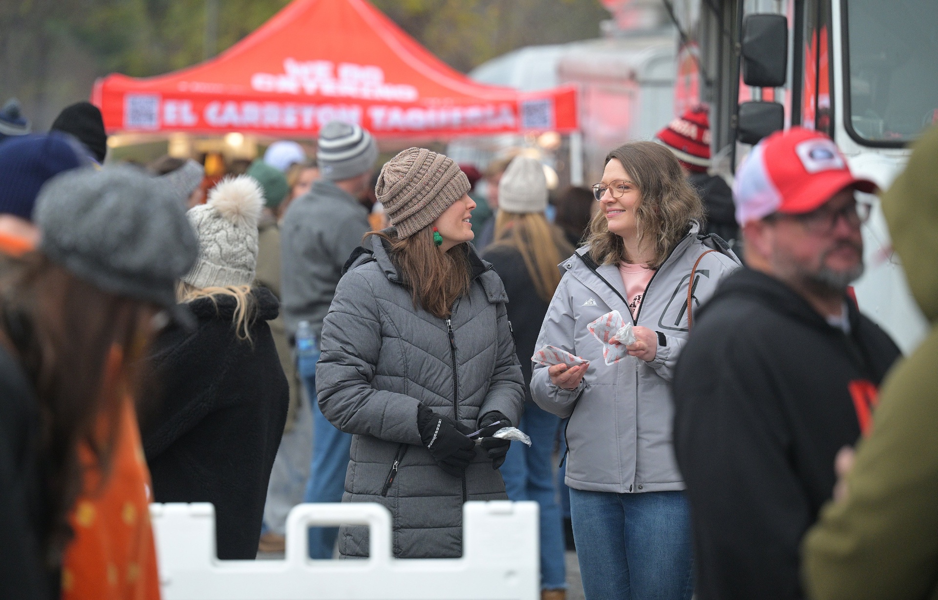 Friends chatting in front of El Carreton Taqueria food tent