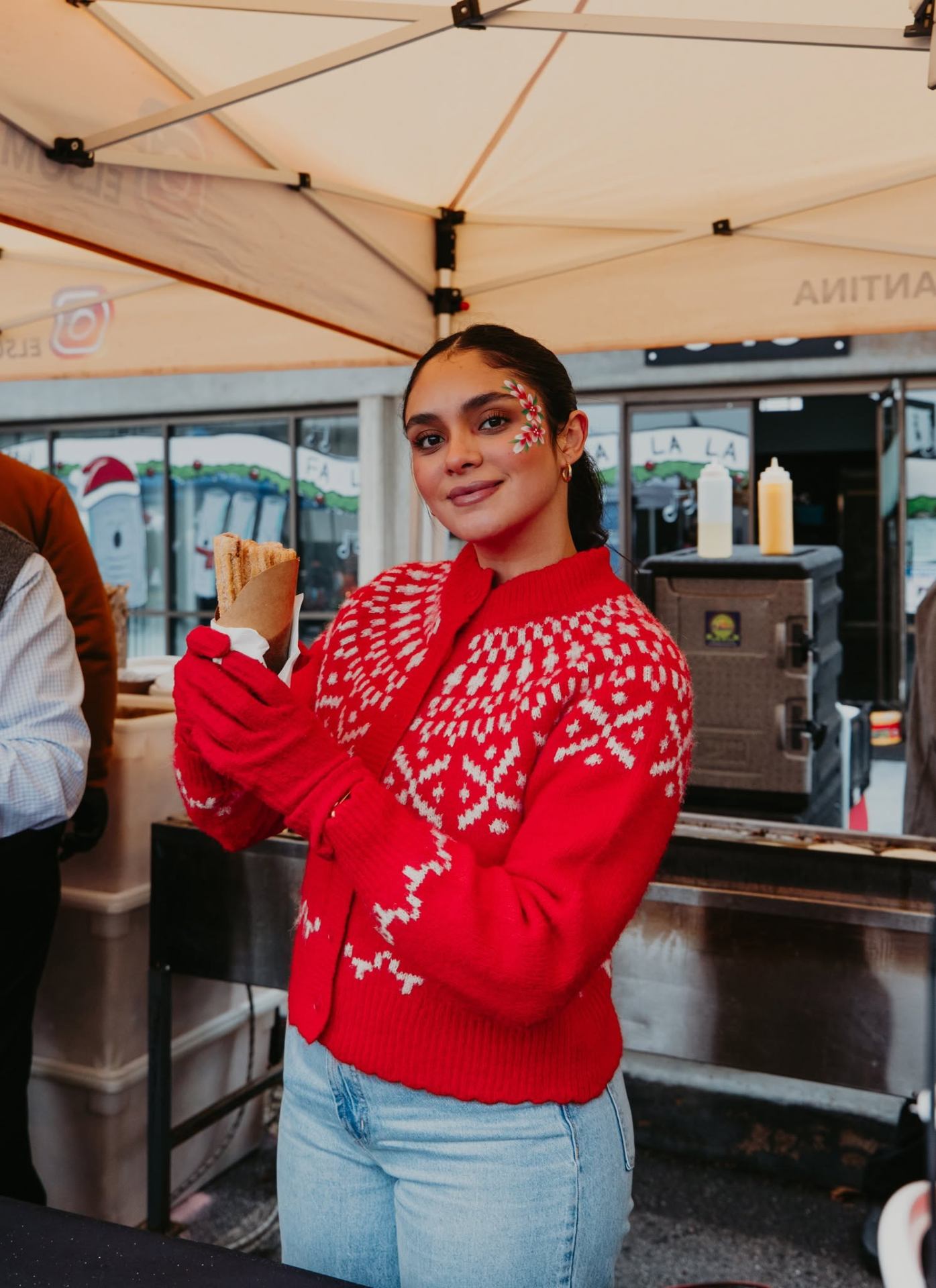 Vendor in a red snowflake sweater holding a churro
